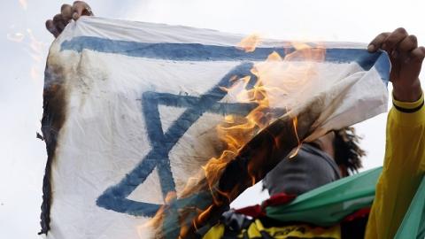 A pro-Palestinian demonstrator holds up a burning Israeli flag on the Republique square in Paris on July 26, 2014. (KENZO TRIBOUILLARD/AFP/Getty Images)