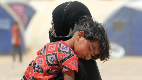 An Iraqi woman displaced from the city of Fallujah carries a child at a newly opened camp where hundreds of displaced Iraqis are taking shelter in Amriyat al-Fallujah on June 27, 2016, south of Fallujah. (AHMAD AL-RUBAYE/AFP/Getty Images)