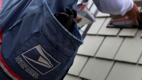 US Postal Service letter carrier places letters in a mailbox as he walks his delivery route July 30, 2009 in San Francisco, California. (Justin Sullivan/Getty Images)