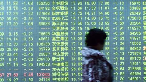 An investor walks past a screen showing stock market movements at a securities firm in Hangzhou, in eastern China's Zhejiang province on January 11, 2016. (STR/AFP/Getty Images)