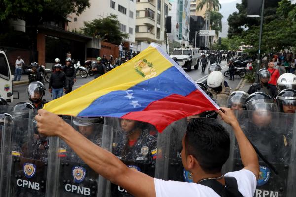 An anti-Maduro demonstrator waves a Venezuelan flag in front of the Venezuelan National Police officers during a demonstration against the government of Nicolás Maduro organized by supporters of Juan Guaidó on March 10, 2020, in Caracas, Venezuela. (Edilzon Gamez/Getty Images)