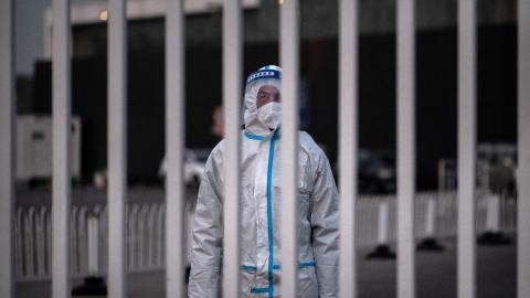 An epidemic control worker guards the gate of a government quarantine facility on December 7, 2022, in Beijing, China. (Kevin Frayer/Getty Images)