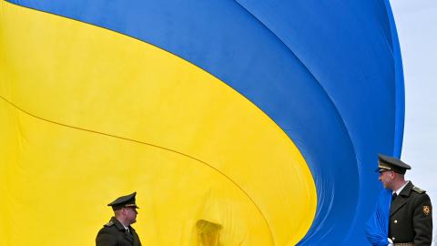 Ukrainian servicemen hold the national flag during a ceremony in Bucha, Ukraine, on March 31, 2023. (Photo by Sergei Supinsky/AFP via Getty Images)