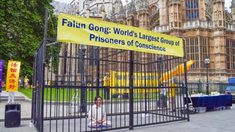A Falun Gong demonstrator sits in a cage in London, United Kingdom, on July 18, 2021, during the protest against the Chinese government's persecution. (Vuk Valcic/SOPA Images/LightRocket via Getty Images)
