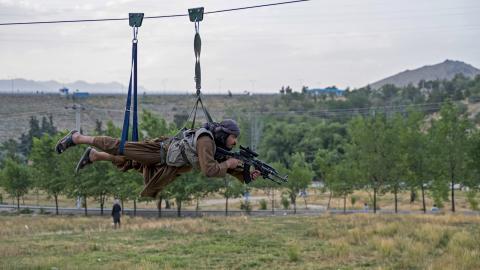 A Taliban security personnel holds his gun as he rides zipline on the outskirts of Kabul on July 4, 2024. (Wakil Kohsar/AFP via Getty Images)