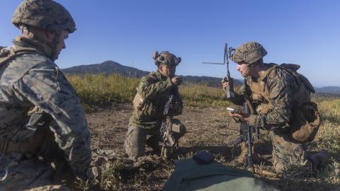 U.S. Marine Corps Sgt. Hunter Heinsohn, left, a signals intelligence operator and analyst, Cpl. Adam Domagalaski, right, an intelligence, surveillance and reconnaissance systems engineer, both with 3rd Radio Battalion, III Marine Expeditionary Force Information Group, coordinate an electronic attack 6-line with Lance Cpl. Jackie Wu, center, a rifleman with 2nd Battalion, 2nd Marine Regiment, 3d Marine Division, during the field training exercise portion of Resolute Dragon 23 at Japan Ground Self-Defense For