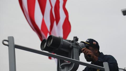 Cmdr. Roosevelt White Jr looks through the “big eyes” on the bridge wing on June 11, 2024. (DVIDS)