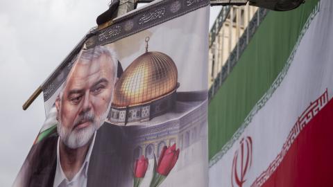 A banner featuring a portrait of Hamas leader Ismail Haniyeh is being hung next to an Iranian flag during a funeral for him and his bodyguard Abu Shaaban in Tehran, Iran, on August 1, 2024. Ismail Haniyeh and his bodyguard, Abu Shaaban, are being killed in an air strike on Haniyeh's residence in northern Tehran the day after the inauguration ceremony of Iran's new president, Masoud Pezeshkian. (Photo by Morteza Nikoubazl/NurPhoto via Getty Images)