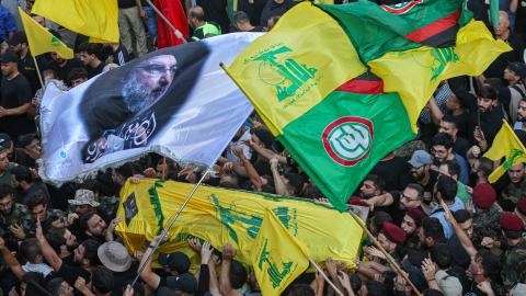 People wave flags as they accompany the casket of slain top Hezbollah commander Fuad Shukr, during his funeral procession in Beirut's southern suburbs on August 1, 2024. Hezbollah on August 1 mourned Shukr, whose body was recovered from the rubble of a July 30 Israeli strike in south Beirut that also killed five civilians, three women and two children, and injured dozens, according to Lebanon's health ministry, as fears mounted of a wider conflict in the region. (Photo by Ibrahim AMRO / AFP) (Photo by IBRAH