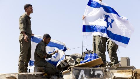 Israeli soldiers hang flags on an armored personnel carrier near the Gaza Strip border on June 6, 2024. (Amir Levy via Getty Images)