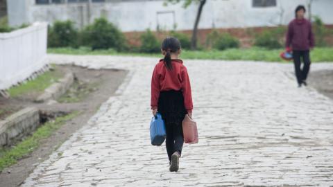 Rear view of a North Korean girl carrying water on a road on May 16, 2009, in Chongsan-ri Cooperative Farm, North Korea. (Eric Lafforgue/Corbis via Getty Images)