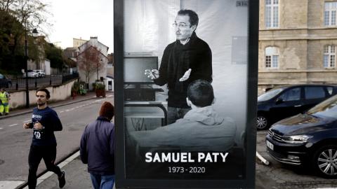 Pedestrians pass by a poster depicting French teacher Samuel Paty in Paris on November 3, 2020. (Thomas Coex/AFP via Getty Images)