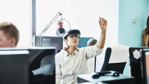 Female engineer testing program on augmented reality headset in computer lab 