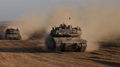 An Israeli soldier gestures from the top of army vehicle near the Israeli border fence with the Gaza Strip, on December 10, 2024, as the war between Israel and Hamas continues in Gaza. (Photo by Menahem KAHANA / AFP) (Photo by MENAHEM KAHANA/AFP via Getty Images)