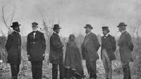 Members of the Peace Commission pose on either side of a Native American woman, wrapped in a blanket, during negotiations for the Treaty of Fort Laramie, at Fort Laramie, Wyoming, in 1868. (Alexander Gardner via Getty Images)