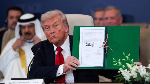 President Donald Trump poses with the signed agreement at a world leaders' summit on ending the Gaza war on October 13, 2025, in Sharm El-Sheikh, Egypt.