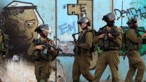 Israeli soldiers in front of the separation-barrier during clashes with Palestinian stone throwers, at the Israeli Qalandiya checkpoint, August 13, 2014. (ABBAS MOMANI/AFP/Getty Images)