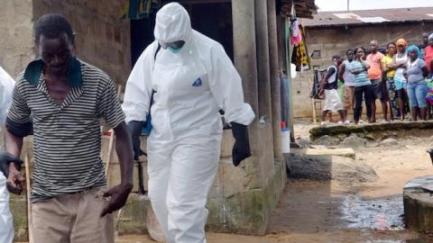 Nurses wearing protective suits escort a man infected with the Ebola virus to a hospital in Monrovia, August 25, 2014. (ZOOM DOSSO/AFP/Getty Images)