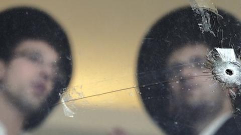 Ultra Orthodox Jews look at bullet holes in the main window of a synagogue in Jerusalem, November 19, 2014. (THOMAS COEX/AFP/Getty Images)