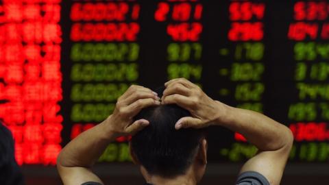 An investor looks at screens showing stock market movements at a securities company in Beijing on July 14, 2015. (GREG BAKER/AFP/Getty Images)
