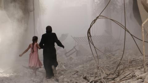 A woman and child run through the smoke after an air-strike staged by Syrian regime forces in Duma district, Damascus, Syria on September 28, 2015. (Mohammed Khair/Anadolu Agency/Getty Images)