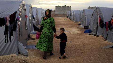 A Kurdish refugee mother and son from the Syrian town of Kobani walk beside their tent in a camp on the Turkish-Syrian border on October 19, 2014 in Sanliurfa, Turkey. (Gokhan Sahin/Getty Images)