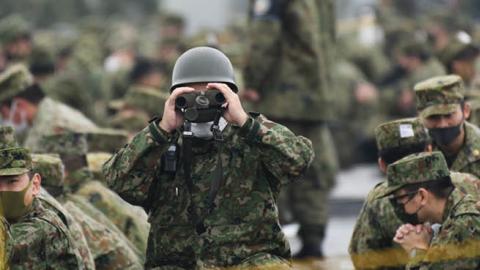 A Japan's Ground Self-Defense Forces (JGSDF) soldier uses binoculars during a live fire exercise at JGSDF's training grounds in the East Fuji Maneuver Area on May 22, 2021 in Gotemba, Shizuoka, Japan (Photo by Akio Kon - Pool/Getty Images)