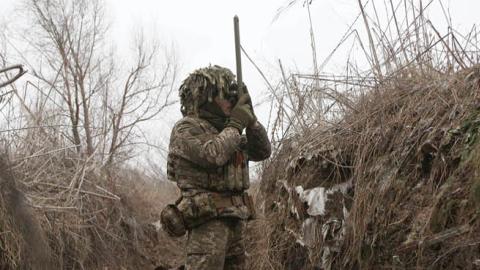 A Ukrainian Military Forces serviceman watches through spyglass in a trench on the frontline with Russia-backed separatists near to Avdiivka, southeastern Ukraine, on January 9, 2022. (Photo by ANATOLII STEPANOV/AFP via Getty Images)