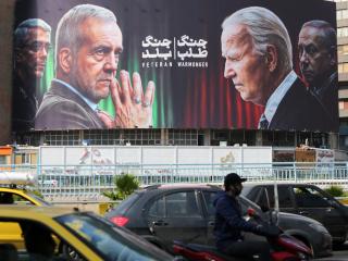 Commuters drive past a billboard bearing pictures of Masoud Pezeshkian, Mohammad Bagheri, and Benjamin Netanyahu in Tehran on October 27, 2024. (Atta Kenare via Getty Images)