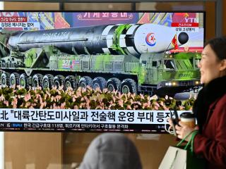 A woman walks past a television screen showing a news broadcast of a North Korean military parade showcasing a record number of nuclear and intercontinental ballistic missiles in Seoul on February 9, 2023. (Jung Yeon-je/AFP via Getty Images)