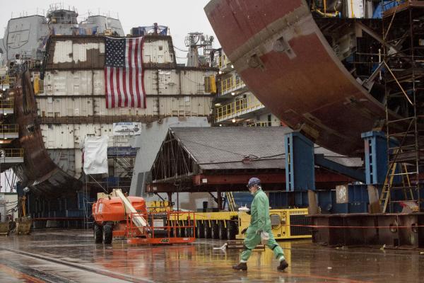 A shipbuilder walks in the yard, with partial ship assemblies behind him, at Bath Iron Works in Bath on Wednesday, December 10, 2014. (Photo by Carl D. Walsh/Portland Portland Press Herald via Getty Images)