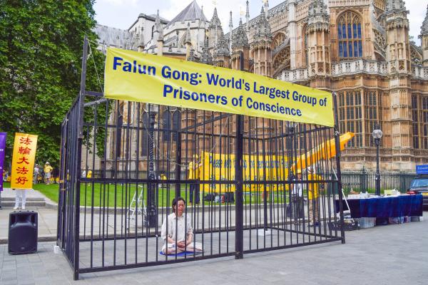 A Falun Gong demonstrator sits in a cage in London, United Kingdom, on July 18, 2021, during the protest against the Chinese government's persecution. (Vuk Valcic/SOPA Images/LightRocket via Getty Images)
