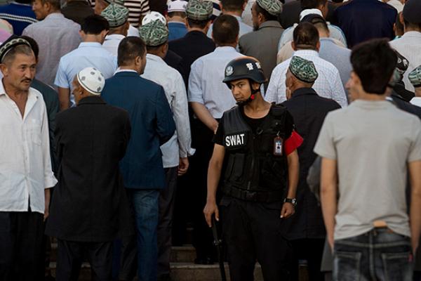 A policeman standing guard as Muslims arrive for the Eid al-Fitr morning prayer at the Id Kah Mosque in Kashgar in China's Xinjiang Uighur Autonomous Region (JOHANNES EISELE/AFP/Getty Images)
