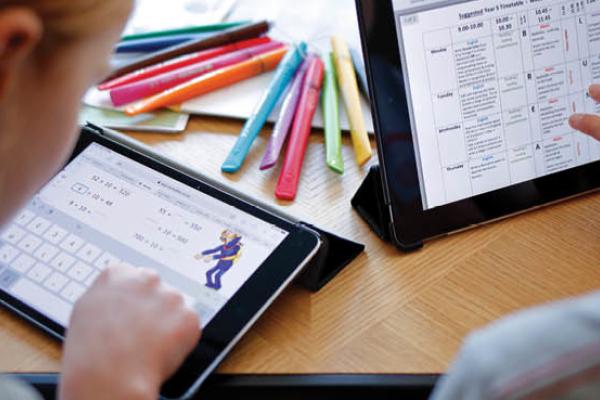 Children use electronic tablets to complete online schoolwork at home. (Getty Images)