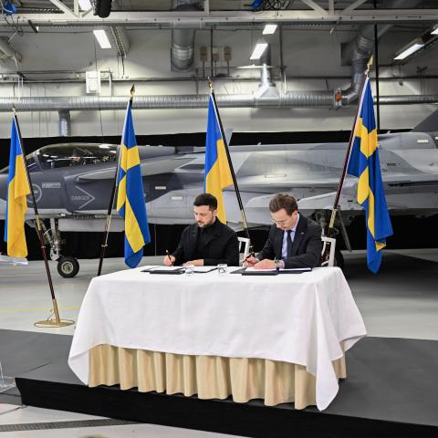 Swedish Prime Minister Ulf Kristersson (R) and Ukrainian President Volodymyr Zelensky sign documents during a joint press conference in front of a Gripen fighter jet in Linkoping, Sweden, on October 22, 2025, after talks on Russia's ongoing of aggression against Ukraine and the countries' deepening defense cooperation. Swedish Prime Minister Ulf Kristersson said on October 22 that Sweden and Ukraine had signed a letter of intent to develop air capabilities, which could see Ukraine buy up to 150 Gripen fight